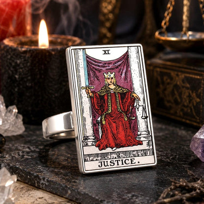 Justice tarot card ring in stainless steel on black marble with a candle, chain and clear quartz