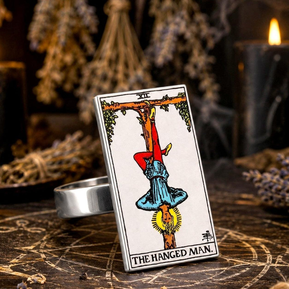The Hanged Man tarot card ring in stainless steel on a pentagram altar with hanging dried herbs