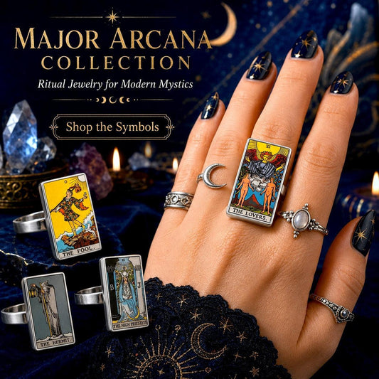 Major Arcana tarot card rings worn on a hand with dark nails beside The Fool and Lovers cards on blue velvet
