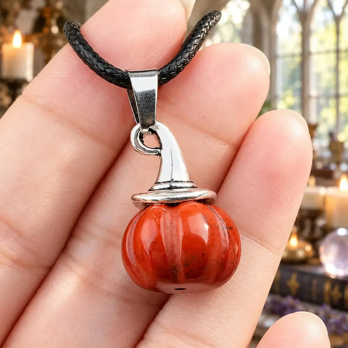 Orange stone pumpkin witch hat pendant held in a hand