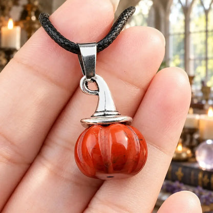 Orange stone pumpkin witch hat pendant held in a hand