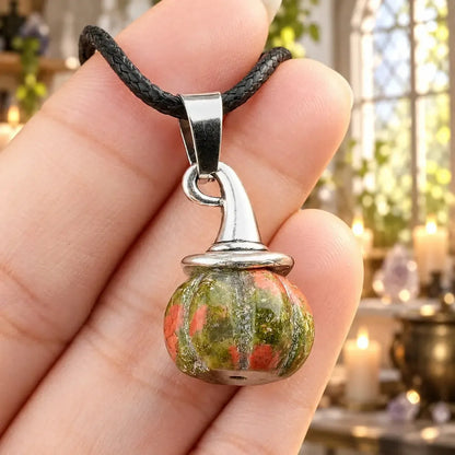 Green and red patterned pumpkin witch hat pendant held in a hand
