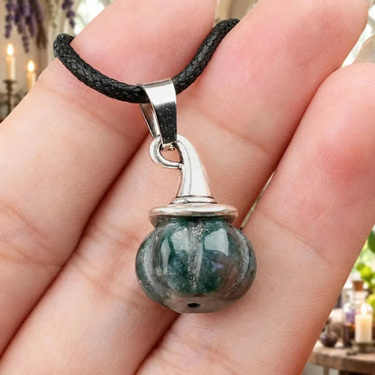 Dark green patterned pumpkin witch hat pendant held in a hand