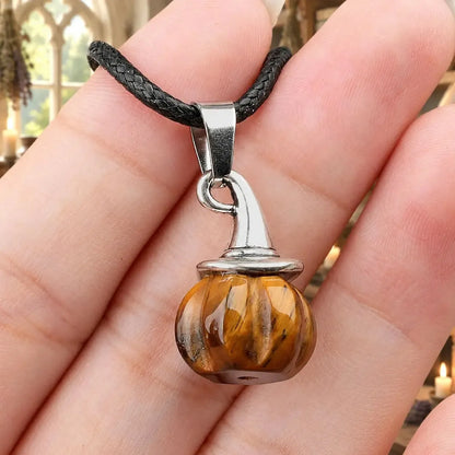 Brown striped pumpkin witch hat pendant held in a hand