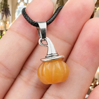 Yellow pumpkin witch hat pendant held in a hand