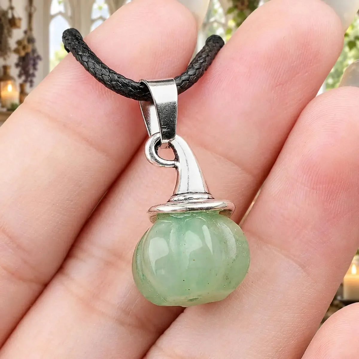 Pale green pumpkin witch hat pendant held in a hand