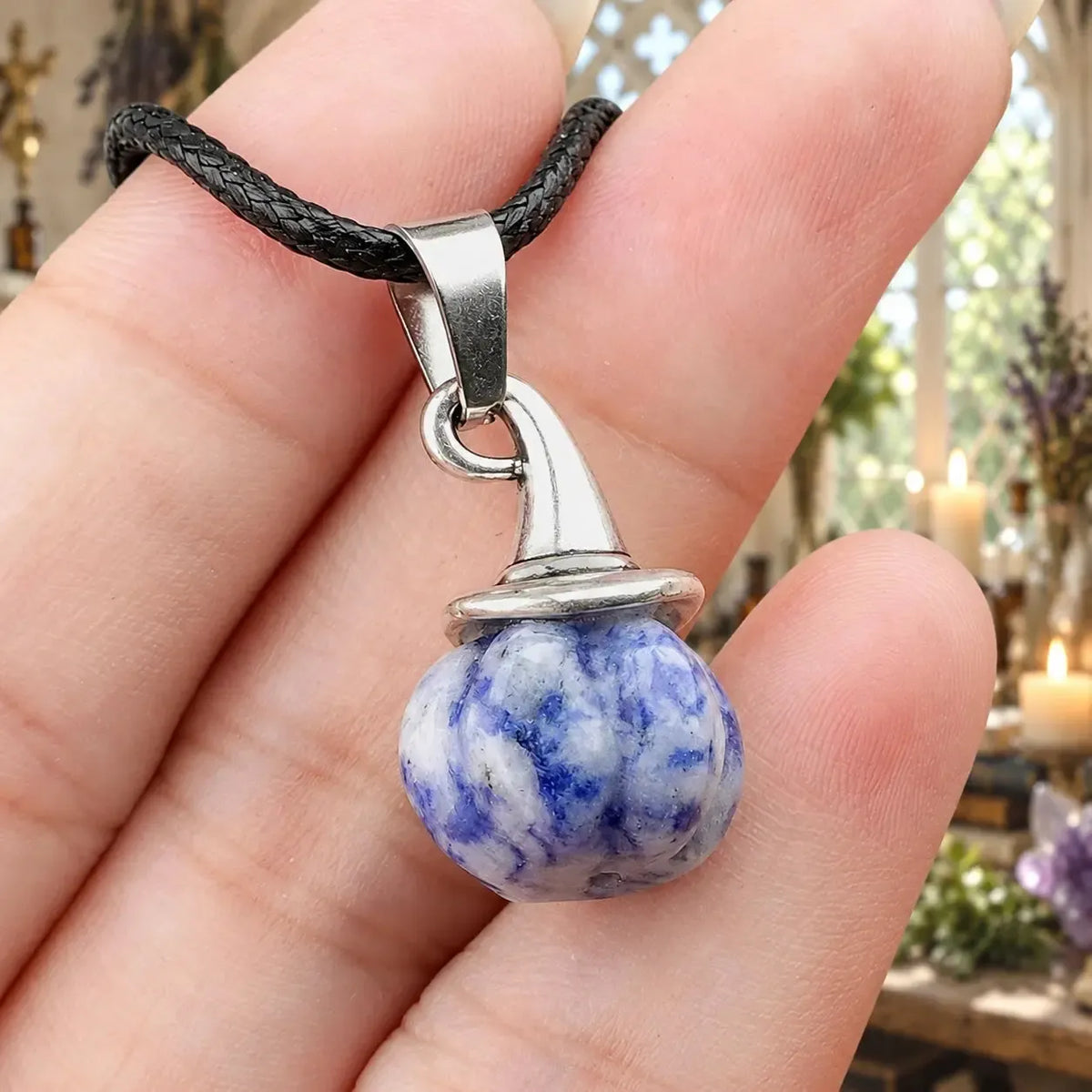 Blue and white patterned pumpkin witch hat pendant held in a hand