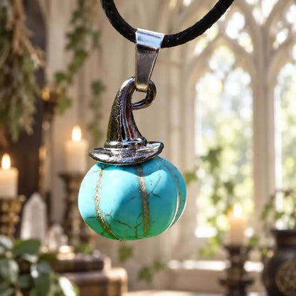 Turquoise-colored pumpkin witch hat pendant against green foliage