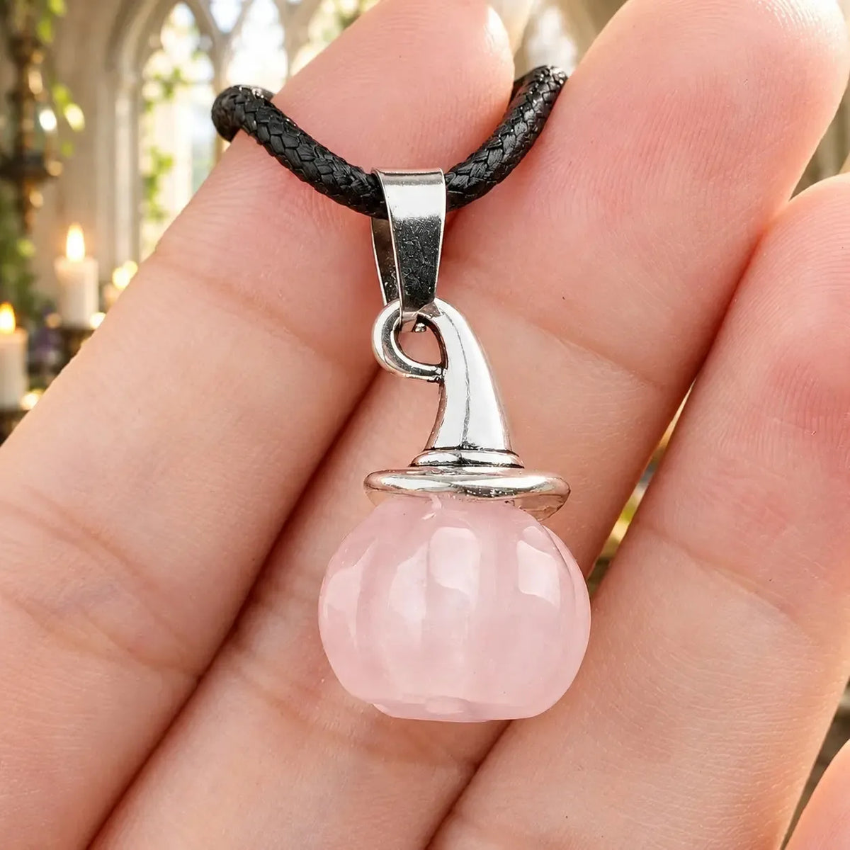 Pink stone pumpkin witch hat pendant held in a hand