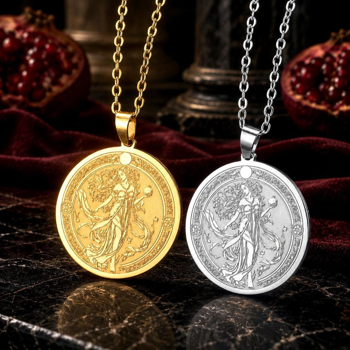 Two round pendant necklaces with detailed engraved figures are displayed side by side on a dark marble surface. One pendant is gold-toned and the other is silver-toned, both hanging from matching chains.