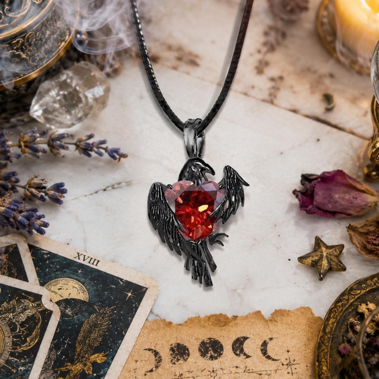 Necklace with a red gemstone and black bird design on a mystical background with tarot cards and crystals.