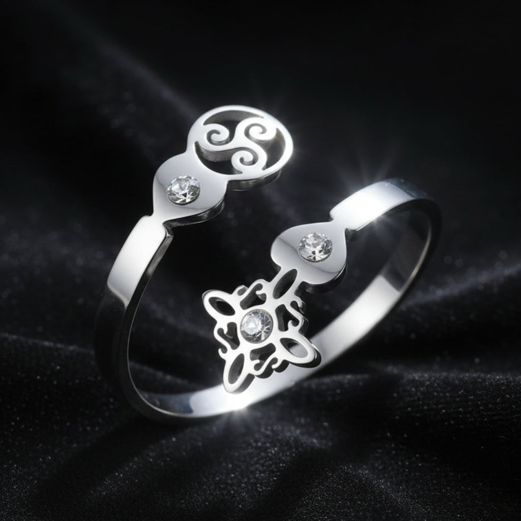Silver Triskele Triple Spiral open ring on black fabric, full band showing Celtic witch knot charm and zircon stones