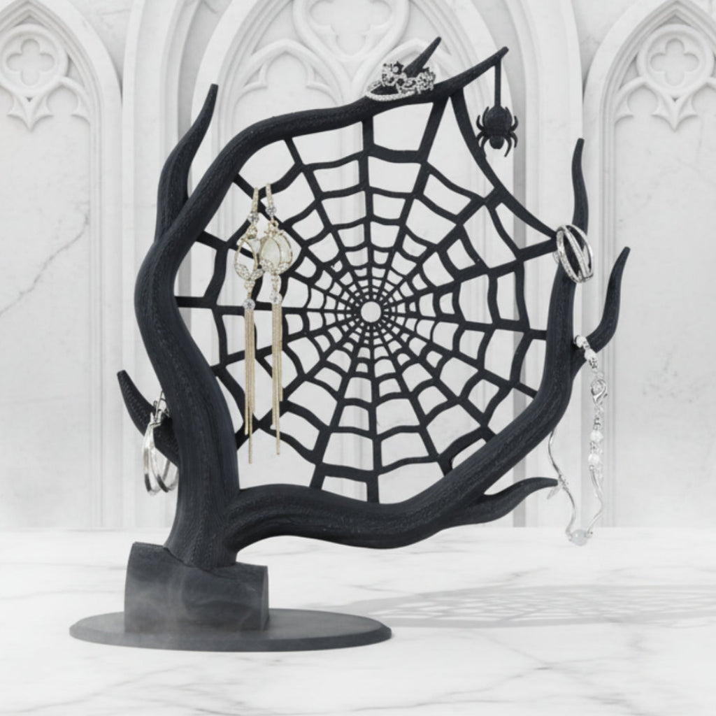 Black spider web jewelry stand with earrings on a white background