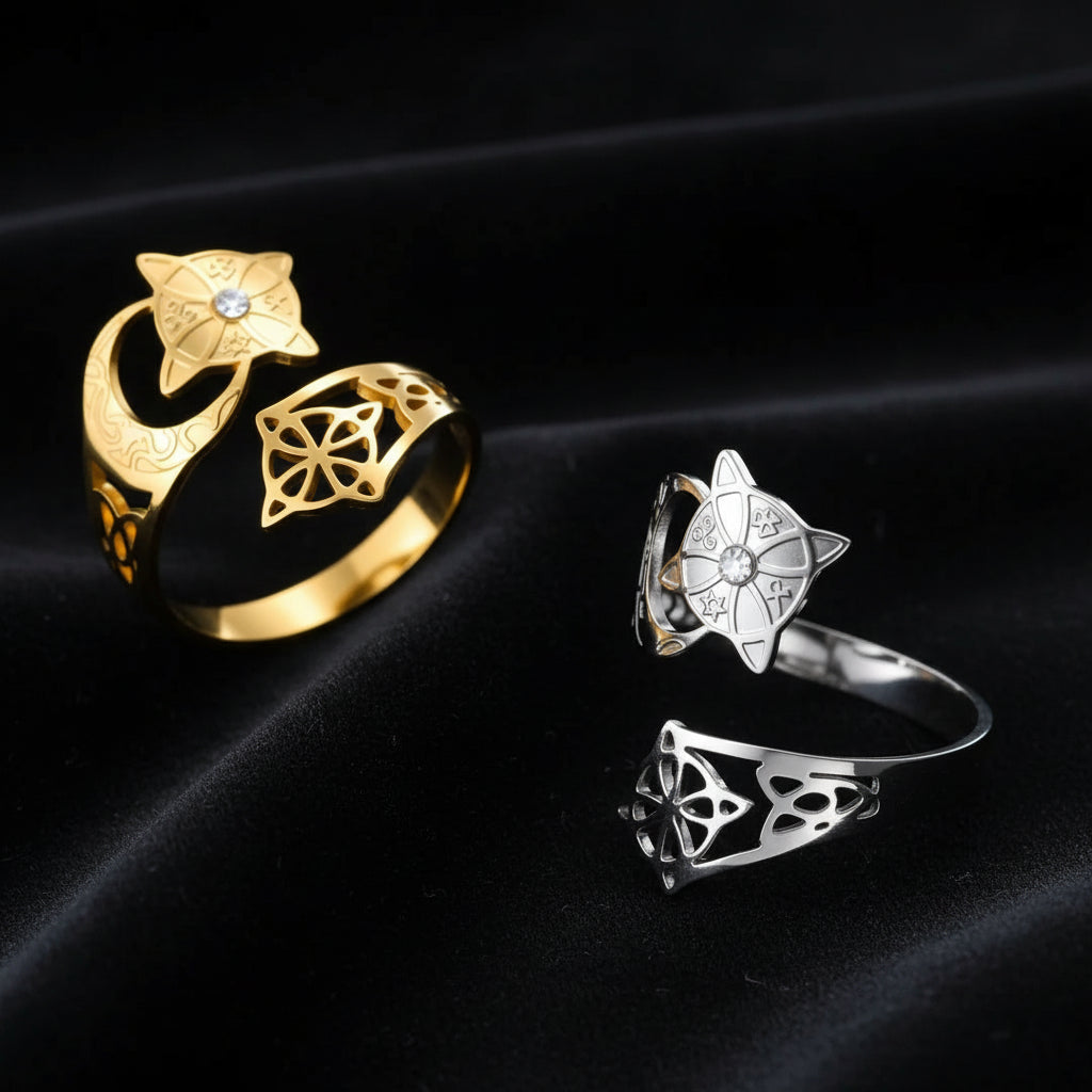 Crescent Moon Celtic Knot Ring in gold and silver on dark textured fabric, the gold ring lying flat and the silver ring standing upright, each with a star medallion, clear stone, and open celtic knot cutout design.