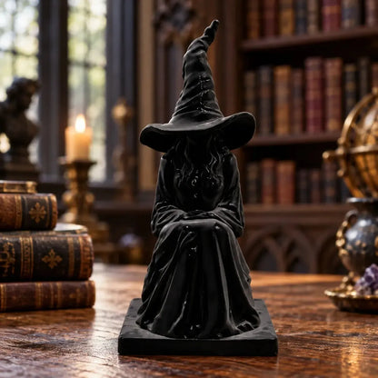 Front view of seated witch figure and pointed hat