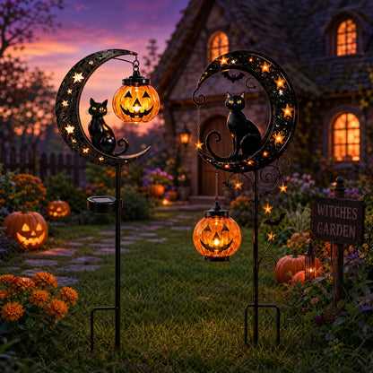 Black cat pumpkin and bat solar stake lights glowing in yard at dusk with witches garden sign