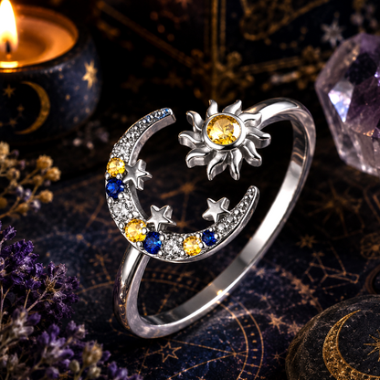 Silver ring with sun, moon, and star design on a mystical background with candles and crystals.