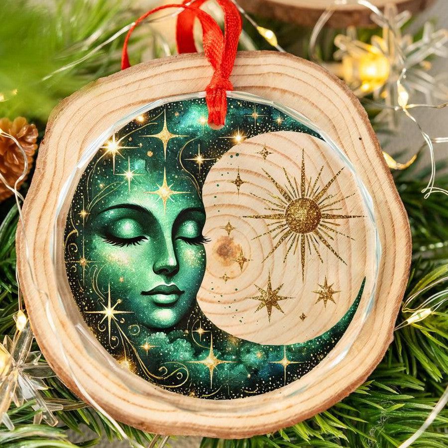 Wood slice ornament with a green goddess face in a starry crescent moon, gold sun, and red ribbon.