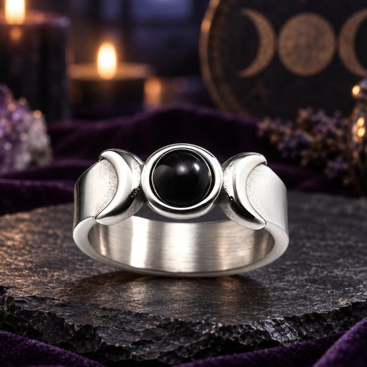 Silver Triple Moon Goddess ring with black onyx and crescent details on a dark Wiccan altar