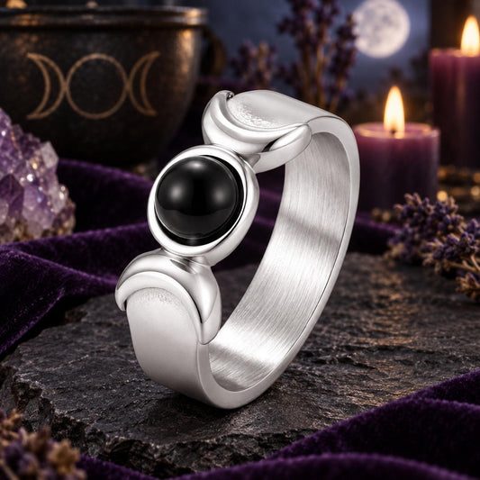 Silver Triple Moon Goddess ring with black onyx and crescent details on a dark Wiccan altar