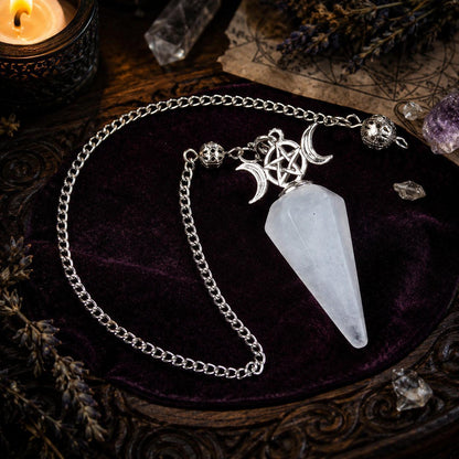 White crystal Triple Moon pendulum on a candlelit Wiccan ritual altar