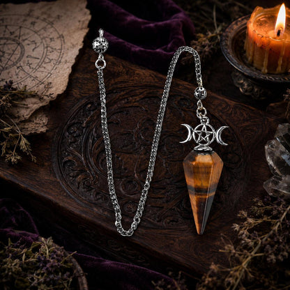 Tiger eye Triple Moon pendulum with complete chain details on a Wiccan altar