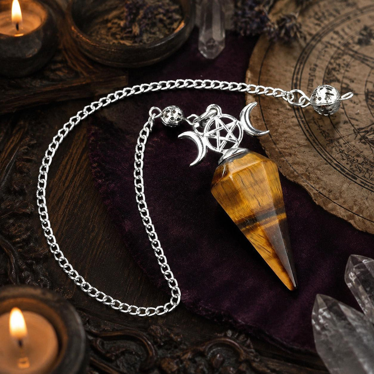 Tiger eye Triple Moon crystal pendulum on a candlelit Wiccan altar