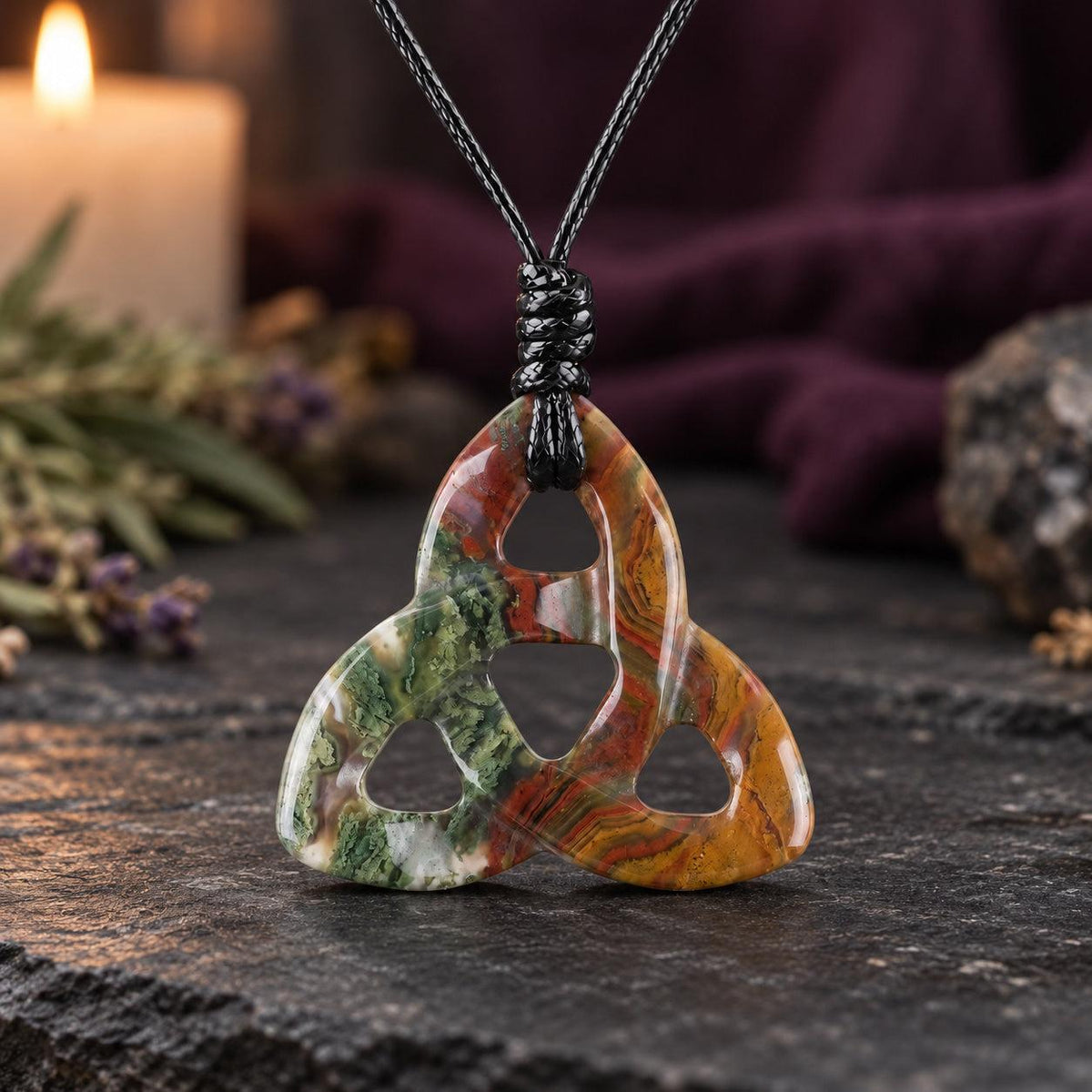 Blue and white marbled triquetra pendant on a knotted cord in a witchy altar setting