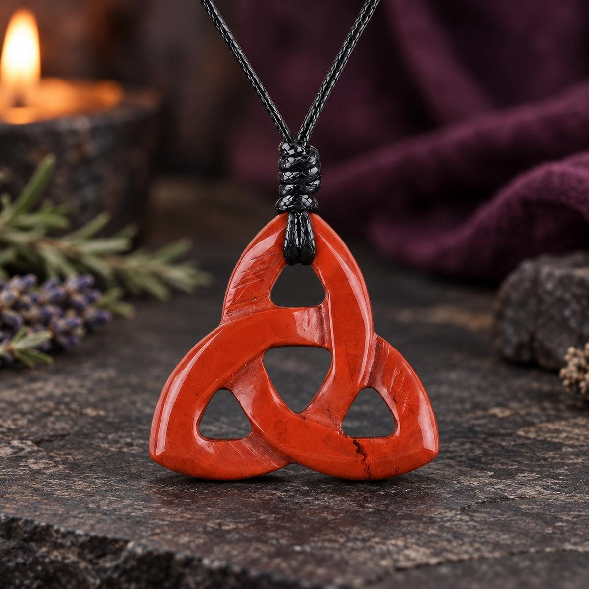 Golden brown banded triquetra stone pendant on a knotted cord in a witchy altar setting