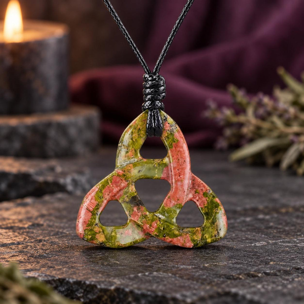Glossy black triquetra stone pendant on a knotted cord in a witchy altar setting