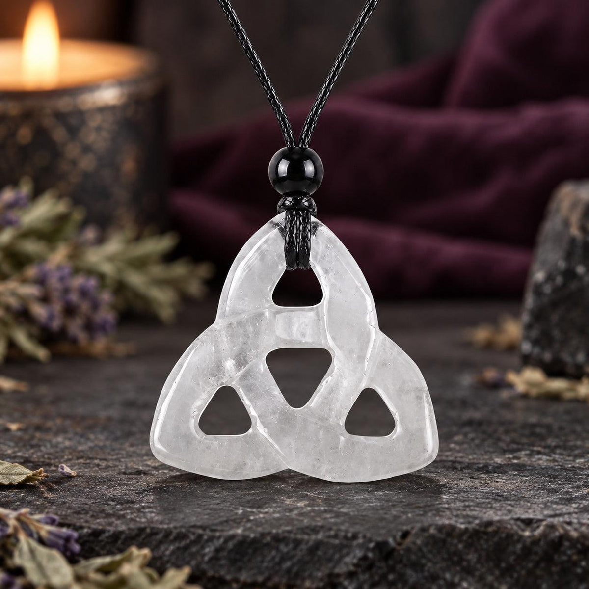 White translucent triquetra stone pendant on a knotted cord in a witchy altar setting