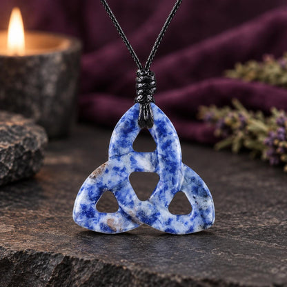 White translucent triquetra stone pendant on a knotted cord in a witchy altar setting