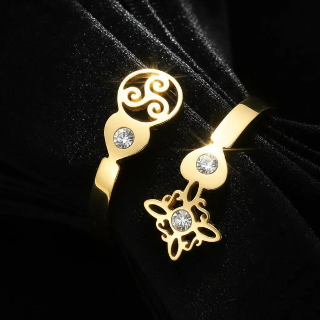 Angled close-up of gold Triskele Triple Spiral open band ring with Celtic witch knot charm and zircon stones