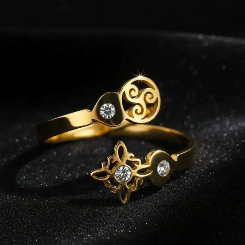 Gold Triskele Triple Spiral open ring on sparkling black fabric, full band showing Celtic witch knot charm and zircon stones