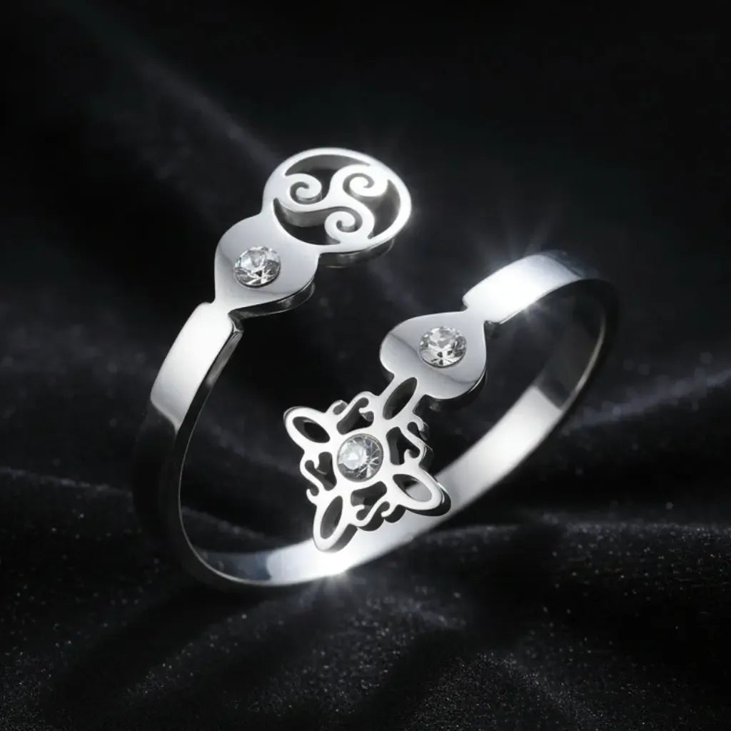 Silver Triskele Triple Spiral open ring on black fabric, full band showing Celtic witch knot charm and zircon stones