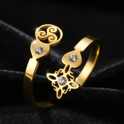 Gold Triskele Triple Spiral open ring with Celtic witch knot charm and clear zircon stones on black fabric