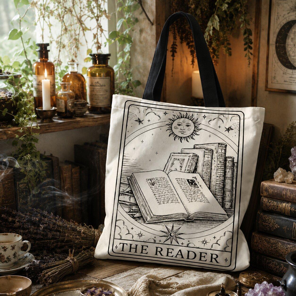 Canvas tote bag printed with 'The Reader': sun and stars at the top, open book and stack of books below.