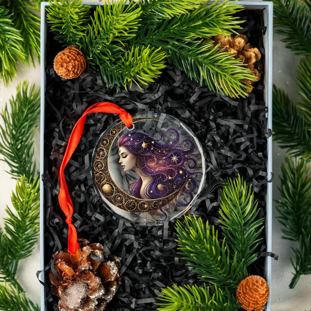 Clear glass Star Moon Goddess ornament with purple hair, gold crescent, red ribbon, in a gift box with pine.