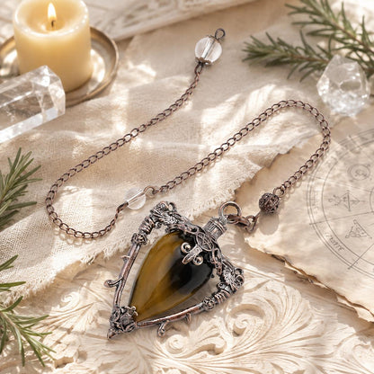 Tiger eye water drop pendulum locket on a bright Pagan ritual altar