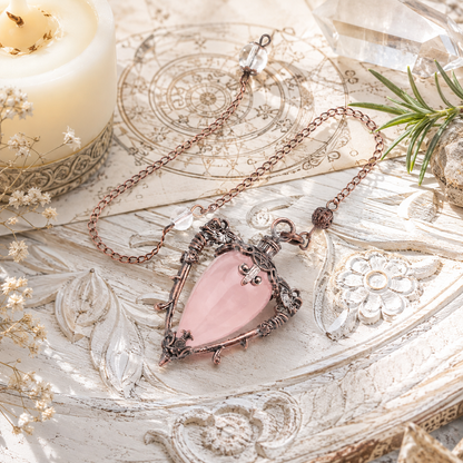 Rose Quartz water drop pendulum locket on a bright Pagan ritual altar