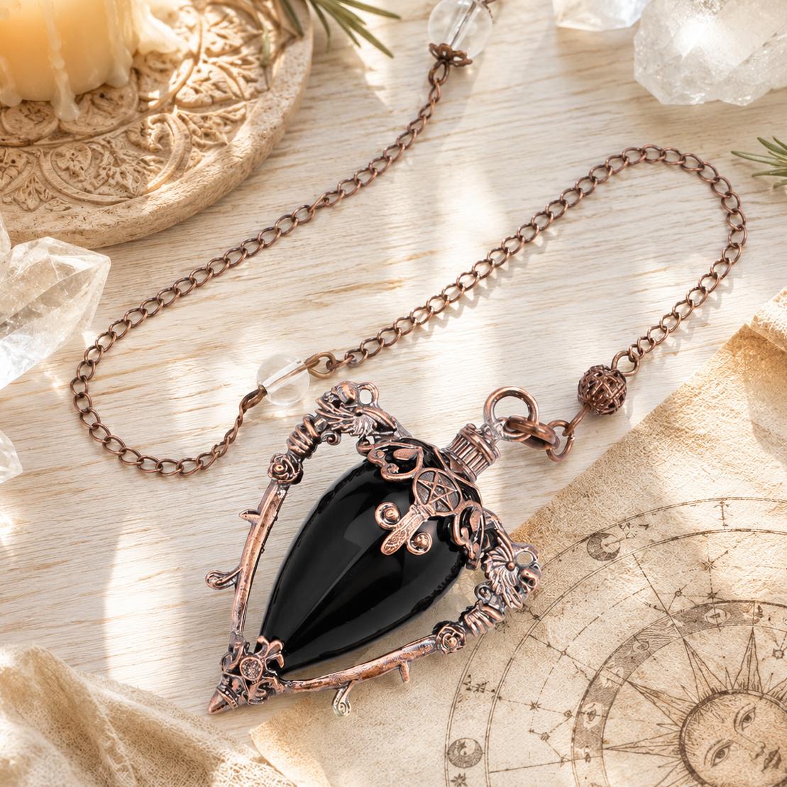 Obsidian water drop pendulum locket on a bright Pagan ritual altar