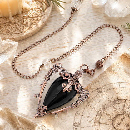 Obsidian water drop pendulum locket on a bright Pagan ritual altar