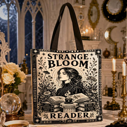 Gothic witchy tote bag printed with "Strange Bloom Reader" text and an art nouveau illustration of a woman reading over a teacup, with stacked books labeled Wild Thoughts, Quiet Magic, Fleeting Words, and Beyond the Page.