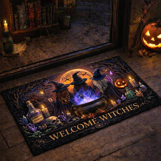 Black "Welcome Witches" doormat with three witches brewing a potion under a full moon, surrounded by candles and a pumpkin.