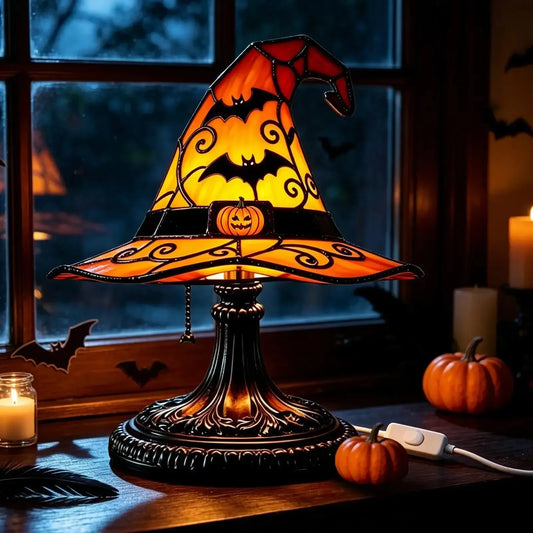 Witch hat table lamp glowing by window at night with candle and mini pumpkins