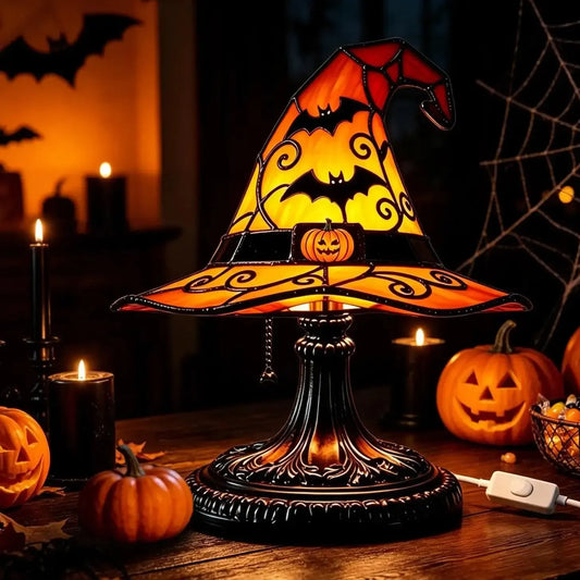 Witch hat table lamp glowing orange with bat cutouts near pumpkins and candles