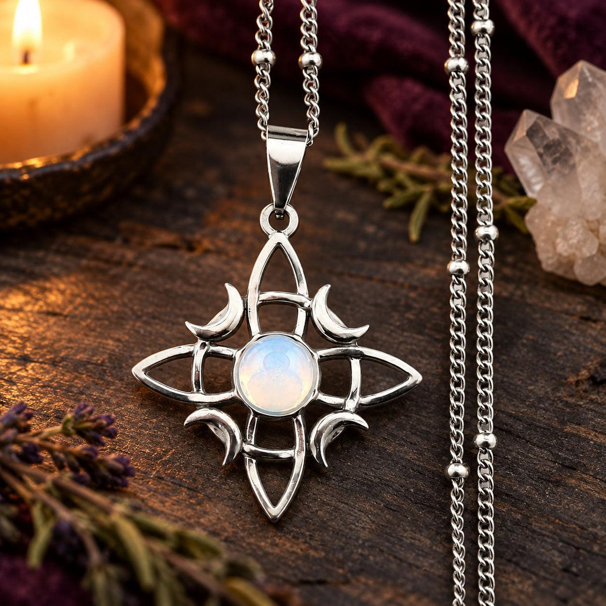 Silver-tone witch knot moon necklace with pale round stone center in a witchy altar setting