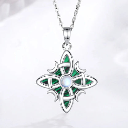 Pendant and chain on pale fabric: Witch Knot Necklace in 925 Sterling Silver, featuring an interwoven witch knot, malachite detail and an artificial moonstone center.