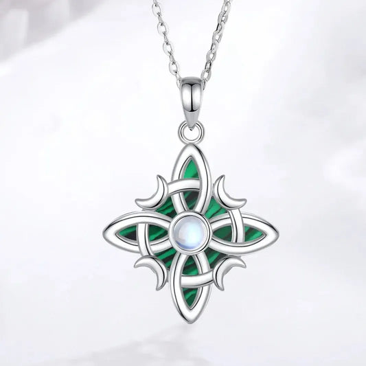 Pendant and chain on pale fabric: Witch Knot Necklace in 925 Sterling Silver, featuring an interwoven witch knot, malachite detail and an artificial moonstone center.