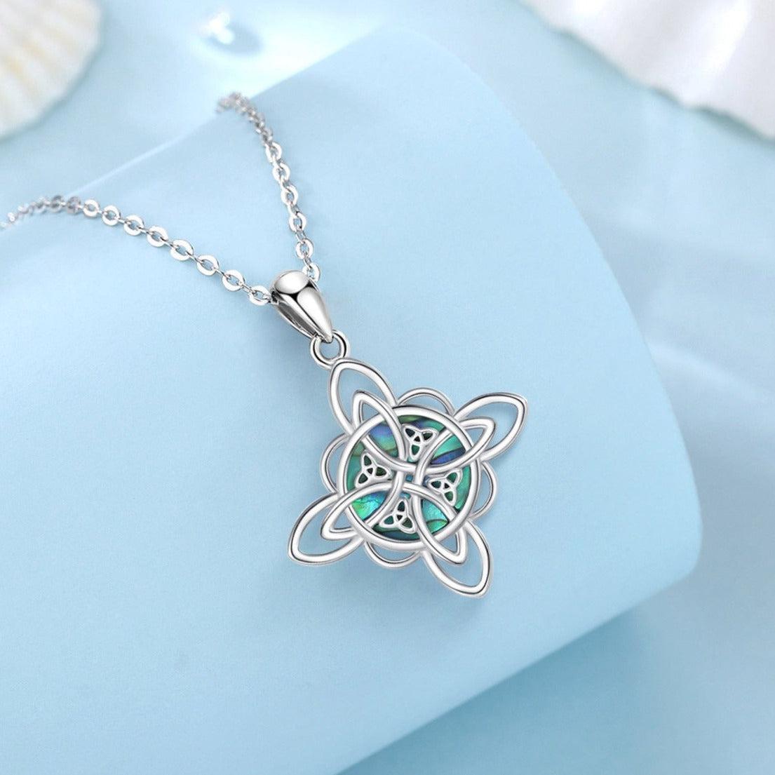 Sterling silver Witch Knot necklace with iridescent abalone shell, symbolizing protection and balance.